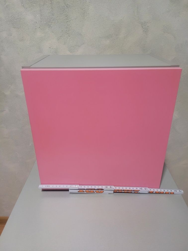 Półka otwierana na ścianę w kolorze różowo-szarym.