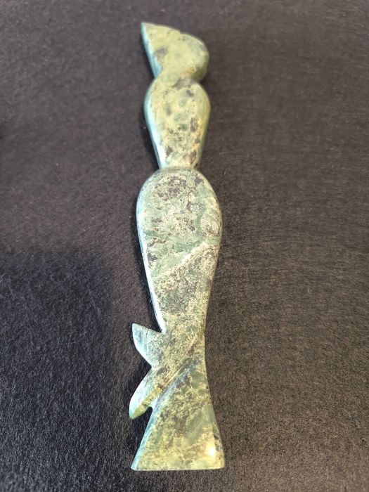 Escultura de mulher em pedra de cor verde.