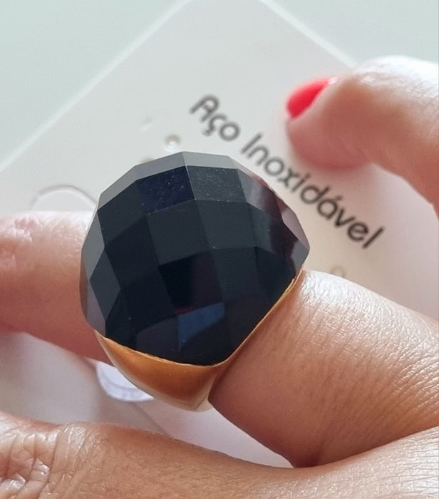 Anel dourado, em aço, com grande pedra preta facetada. T17