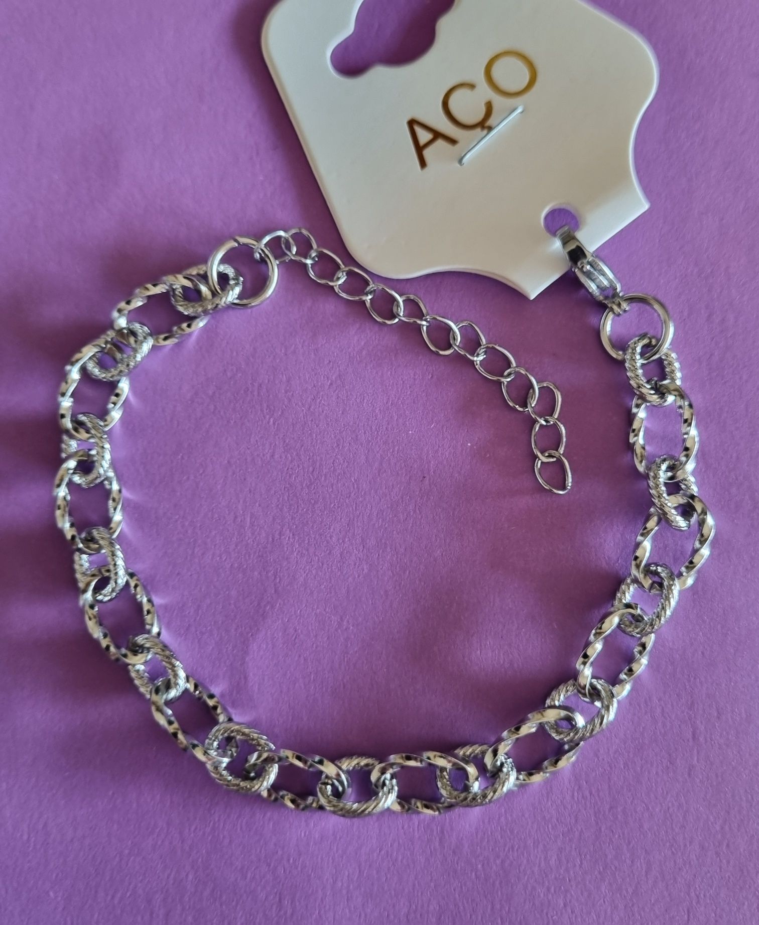 Pulseira prateada, em aço, com elos trabalhados. Tem extensor