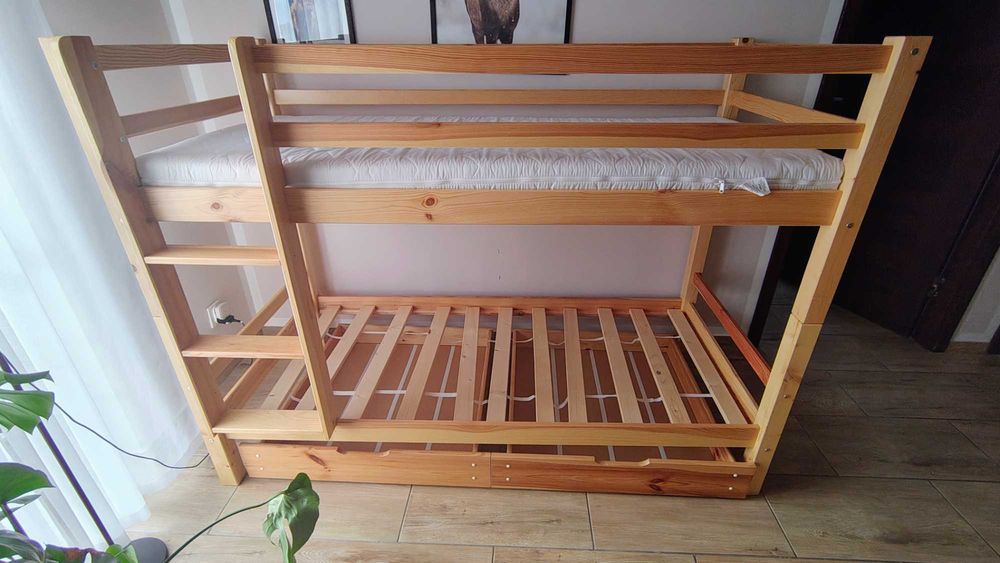 Drewniane łóżko piętrowe z materacami, z dwoma szyfladami.