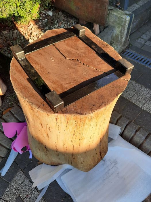 Stolik kawowy z pnia dębu na metalowej podstawie.