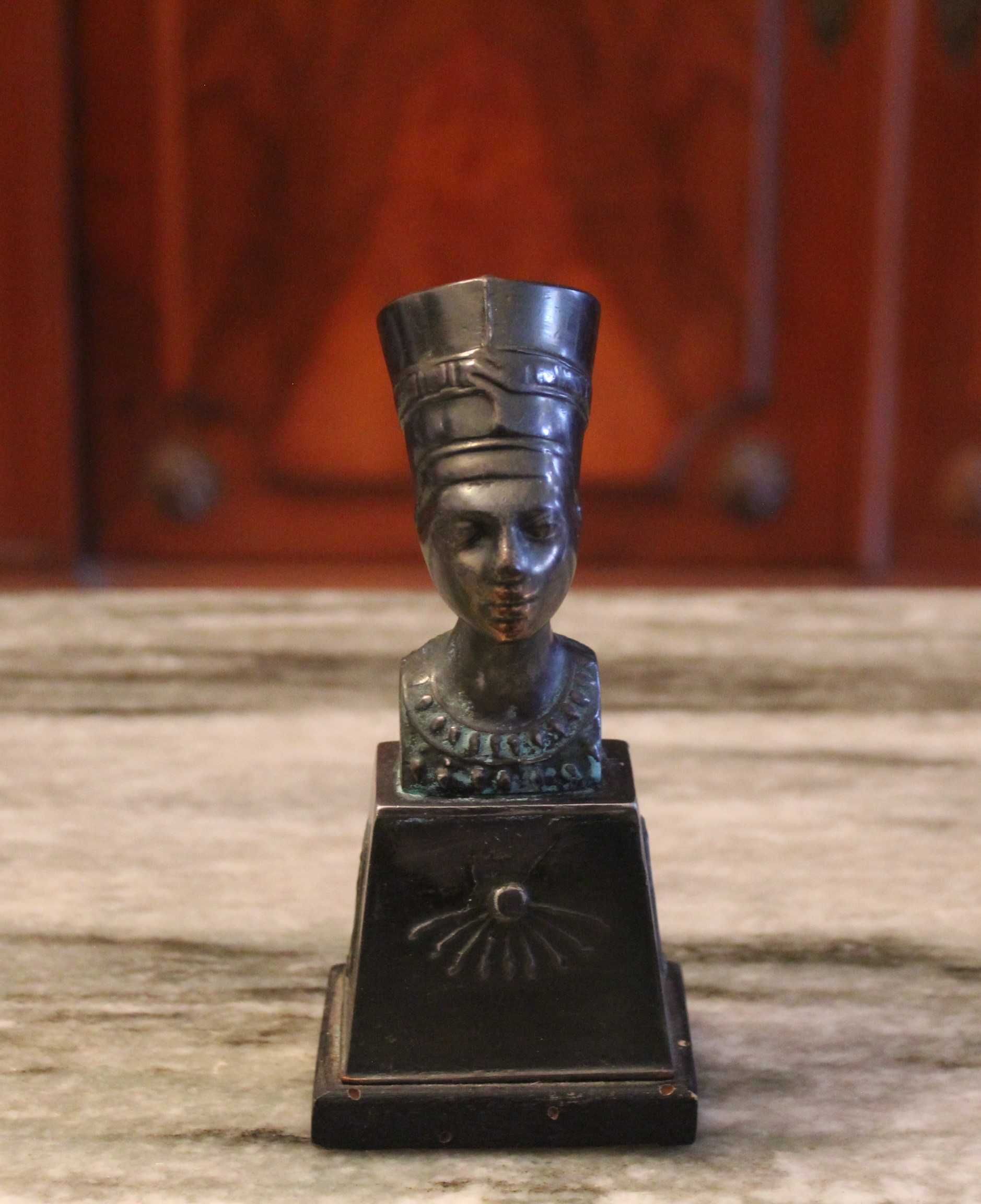 Busto de Nefertiti com 15,5cm de altura em metal sobre madeira.