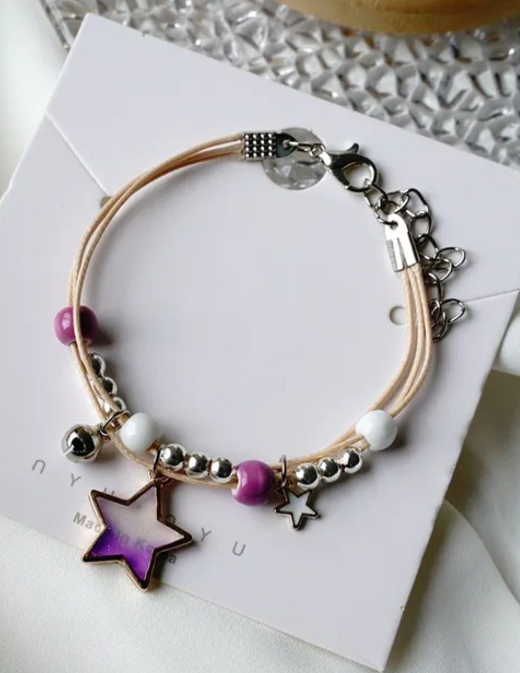 Pulseira/tornozeleira estrelas em tons de lilás, azul e rosa.