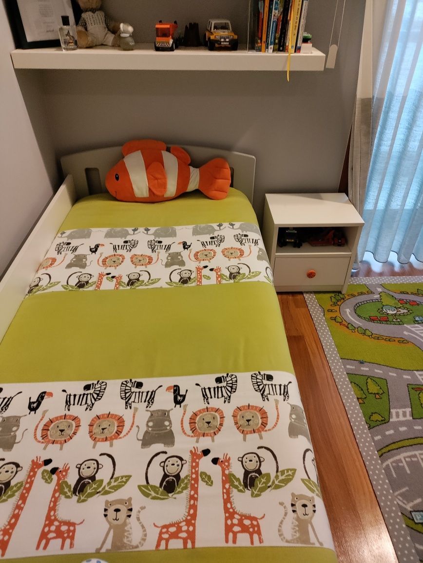 Cama de criança com proteção e mesa de cabeceira