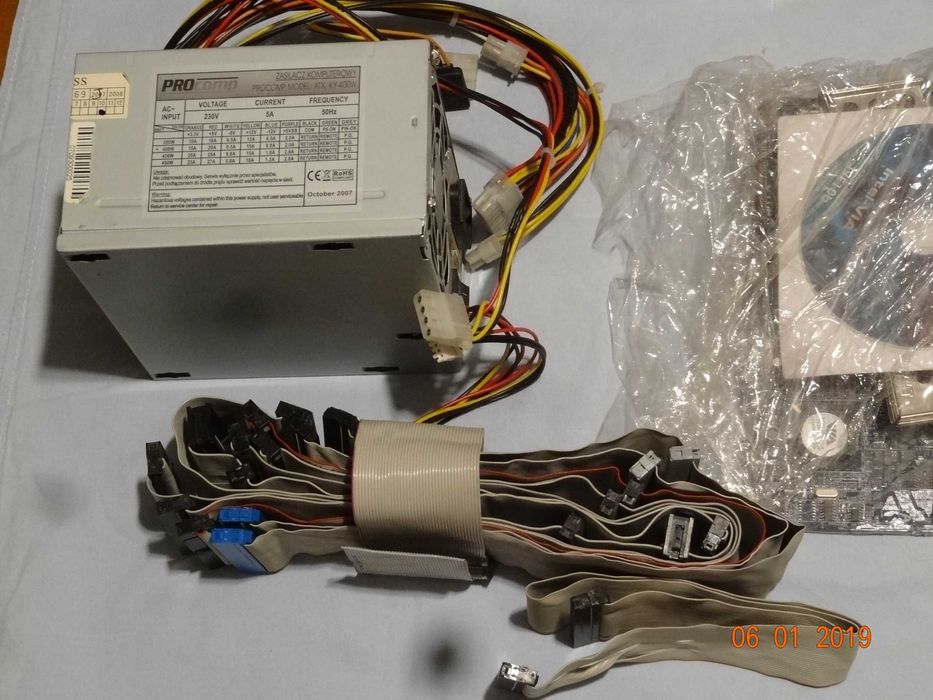 Płyta główna ASRock, zasilacz, CD, kable, moduły.