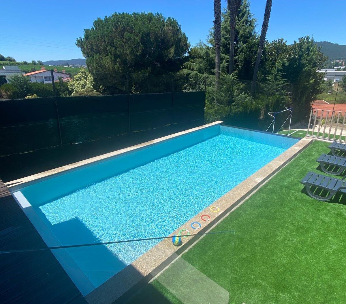 Espaço exterior com piscina e campo de jogos.