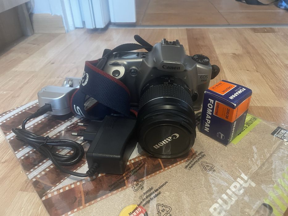 Canon EOS 3000 z kliszą, akumulatorkami, ładowarką i koszulką na neg