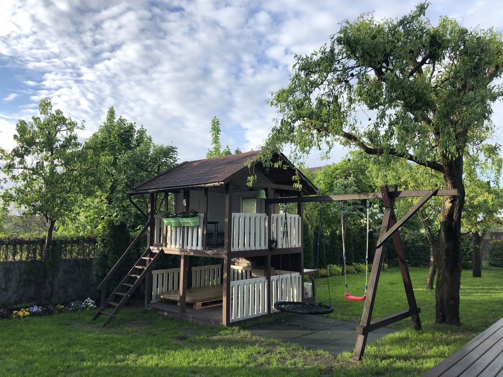 Drewniany domek dla dzieci z huśtawkami, gniazdem i zjeżdżalnią wodną