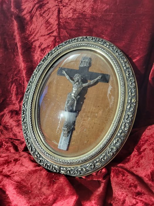 Stary krzyż w owalnej ramie za szkłem