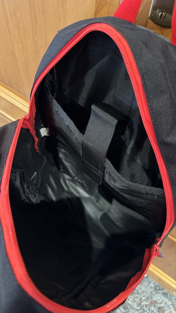 Mochila preta com os fechos em vermelho