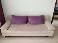 Sofa beżowa z funkcją spania plus fioletowe poduchy