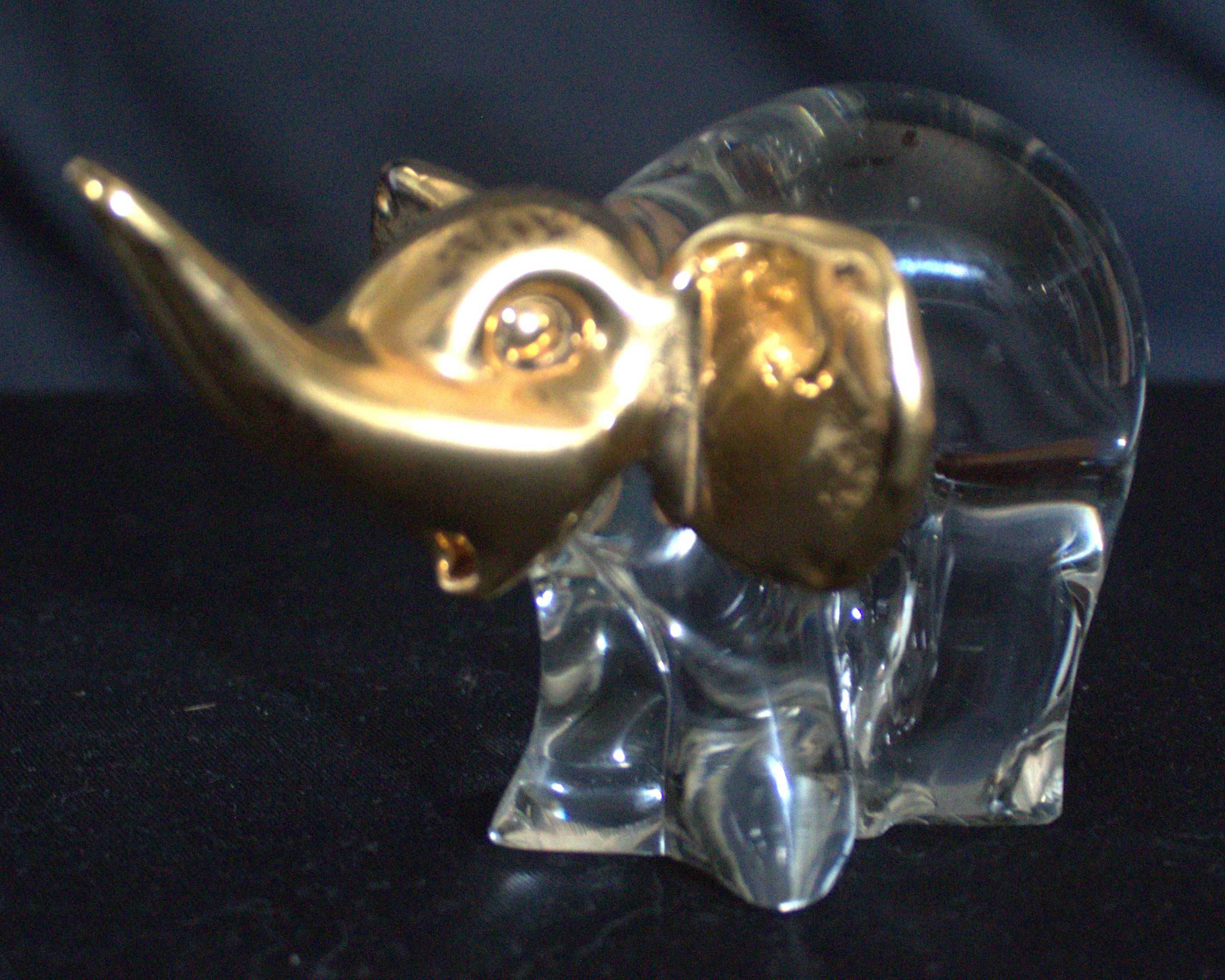 Estatueta de elefante em vidro transparente com detalhes em dourado.
