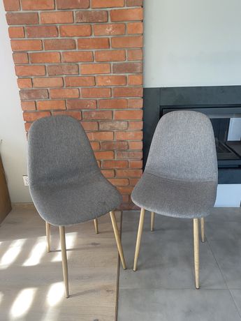 Dwa szare tapicerowane nowoczesne krzesla z drewnianymi jasnymi nogami