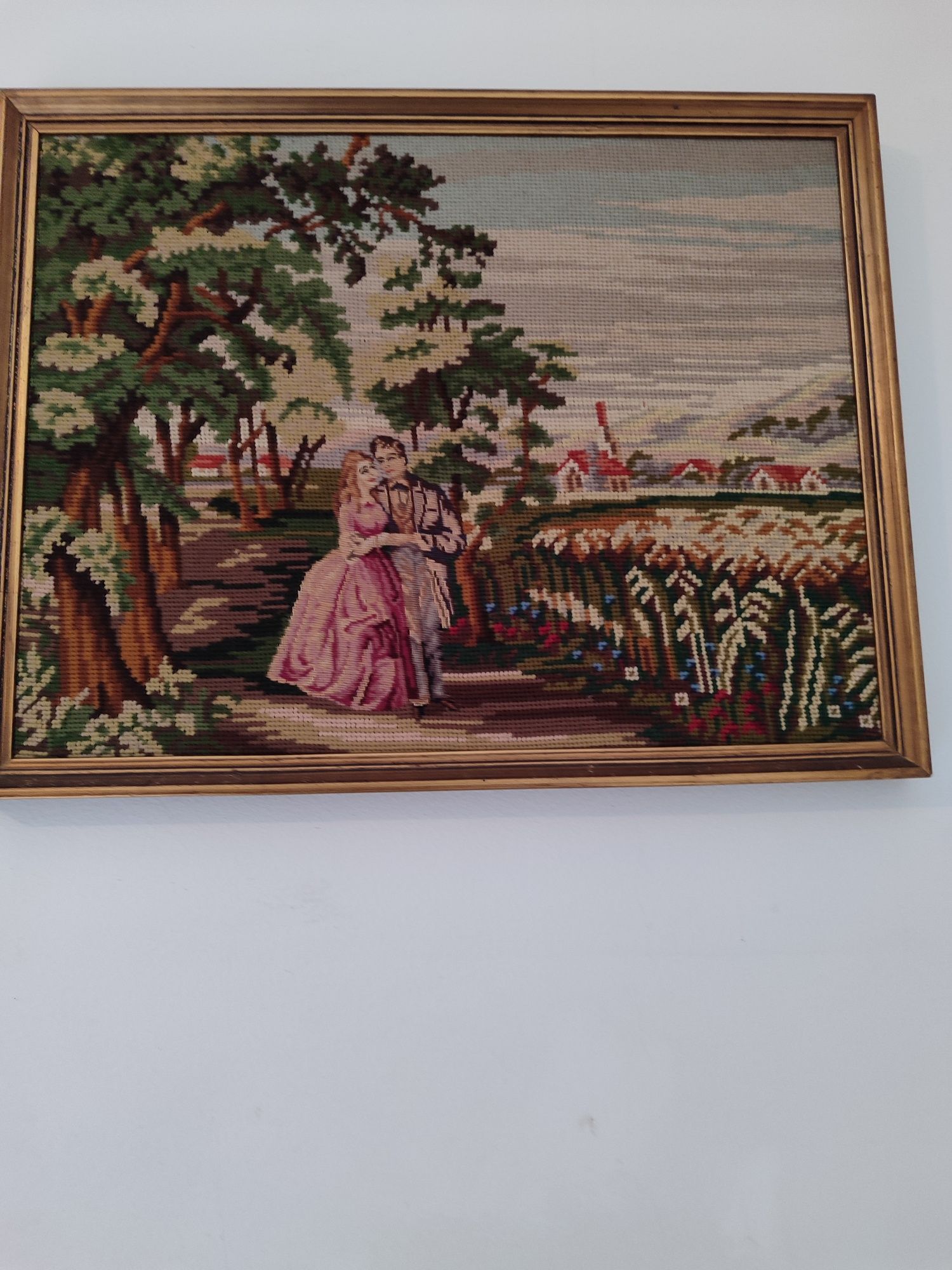 Quadro com imagem de ponto cruz ,com moldura em dourado.