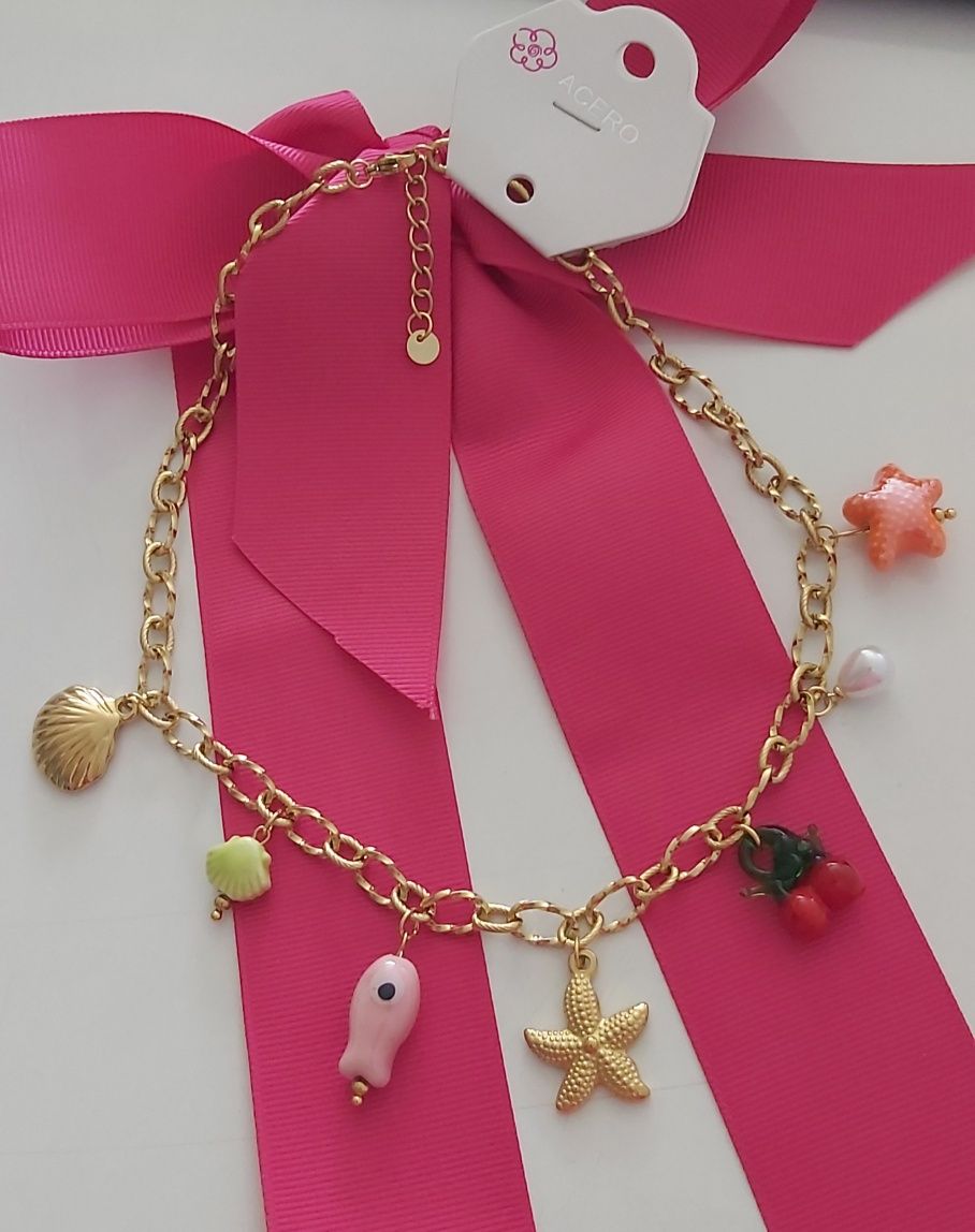 Colar dourado, em aço, com 7 pingentes diferentes. Tem extensor