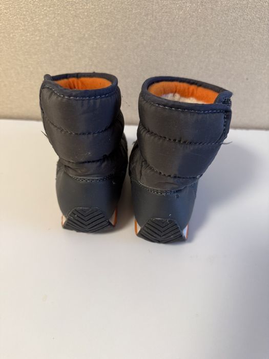 Дитячі зимові сапожки біля дому