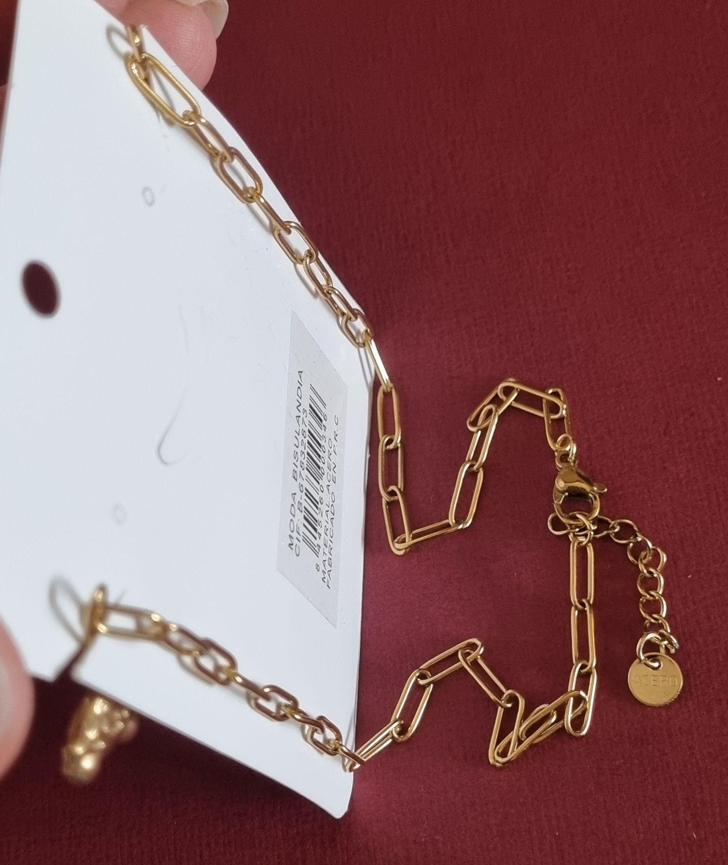 Colar dourado, em aço, com 5 pingentes diferentes. Tem extensor