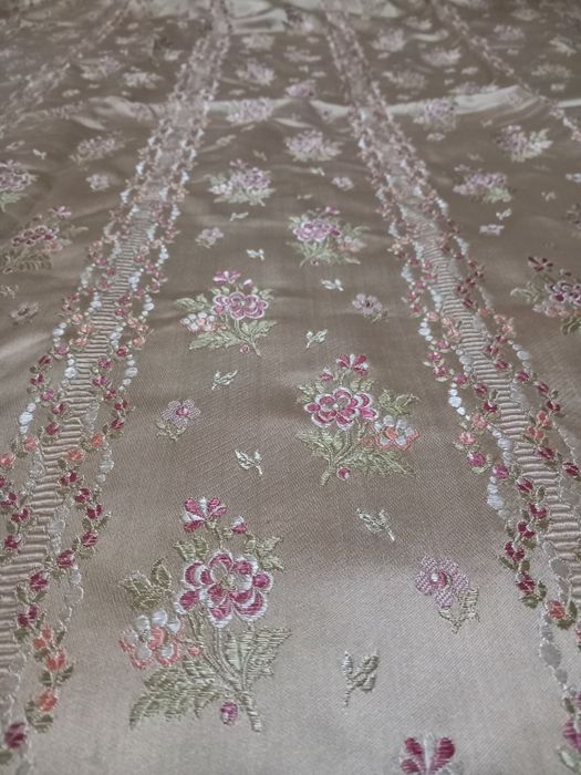 Colcha acetinada antiga com fundo amarelo e bordada com flores.