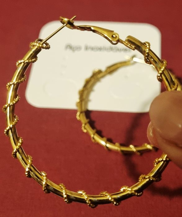 Brincos/argolas douradas, em aço, com cerca de 5cm de comprimento.