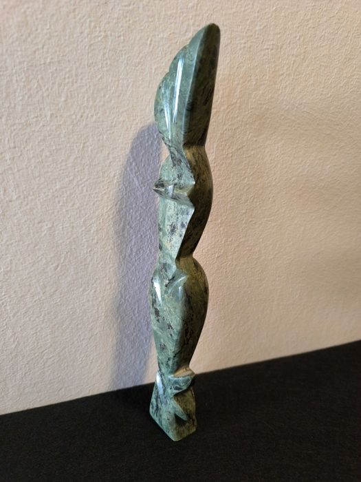 Escultura de mulher em pedra de cor verde.