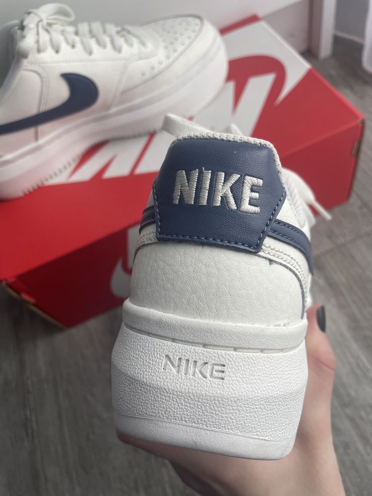 Białe buty Nike z niebieskim znaczkiem