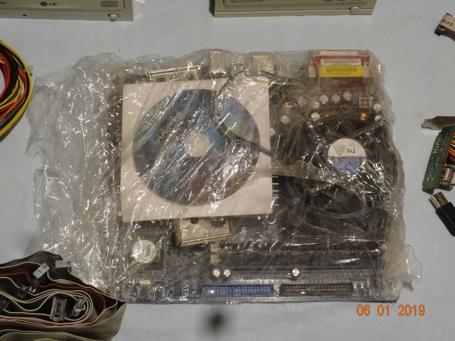 Płyta główna ASRock, zasilacz, CD, kable, moduły.