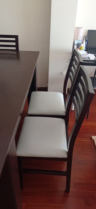 Mesa de madeira castanho escuro com seis cadeiras de pele