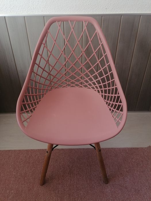 Cadeira rosa com pés de madeira.