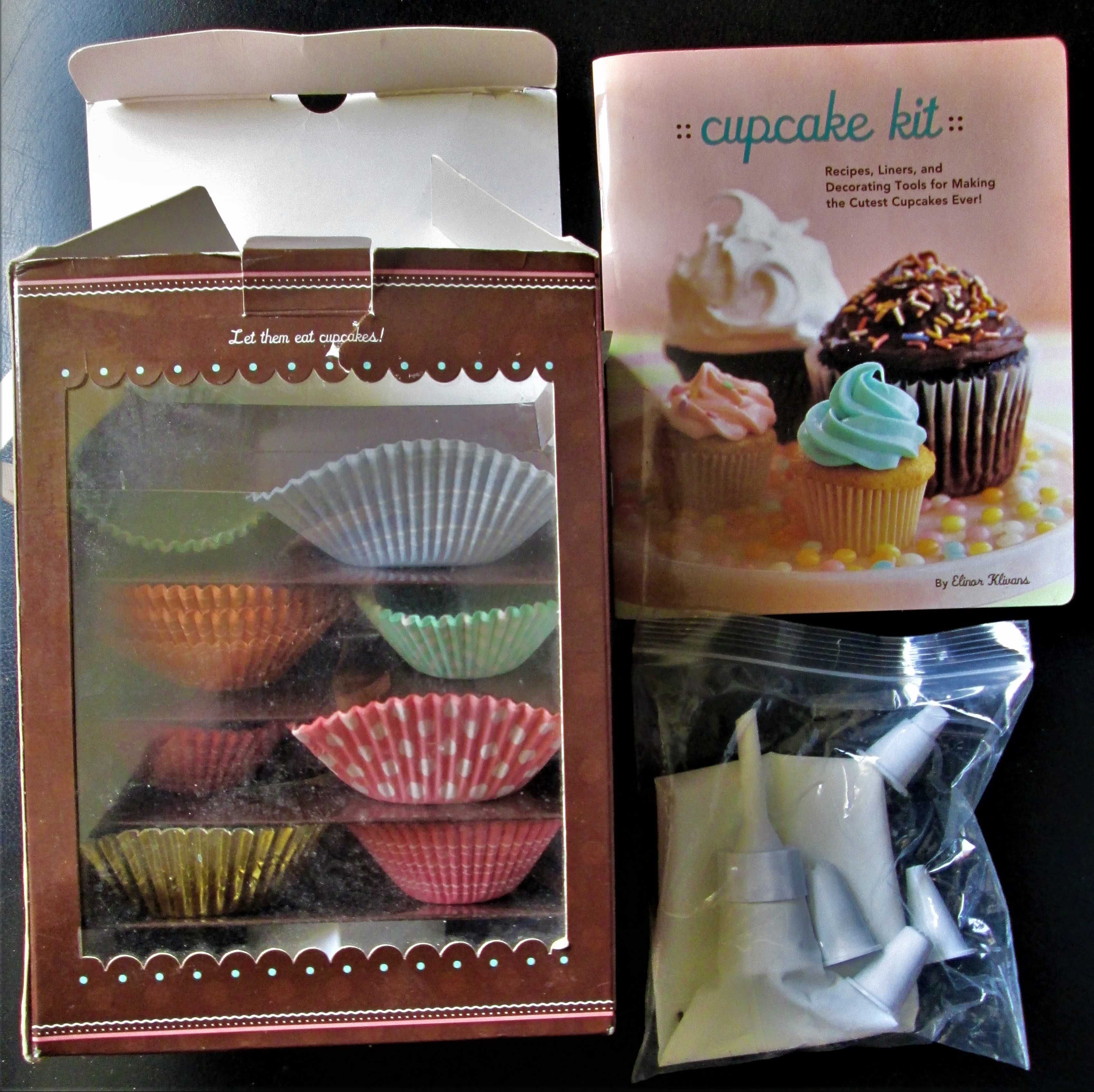 Cupcake, uma caixa com livro de receitas, saco de pasteleiro e formas