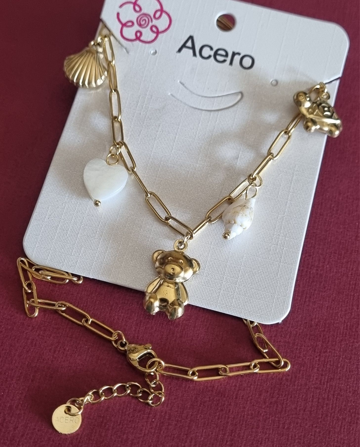 Colar dourado, em aço, com 5 pingentes diferentes. Tem extensor