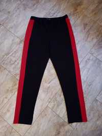 Czarne spodnie damskie z czerwonymi pasami po bokach