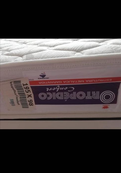 Cama de solteira com mesinha de cabeceira com duas gavetas.