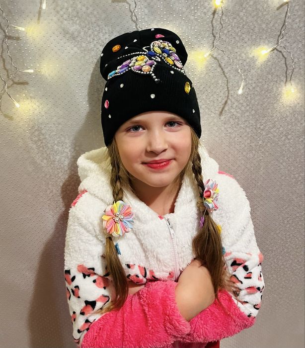 Чорна шапка з яскравим метеликом.