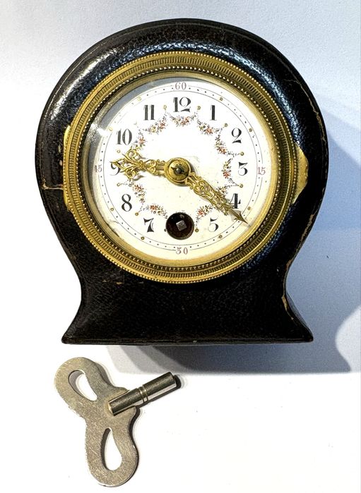 Antigo relógio de viagem com mostrador esmaltado e caixa em couro