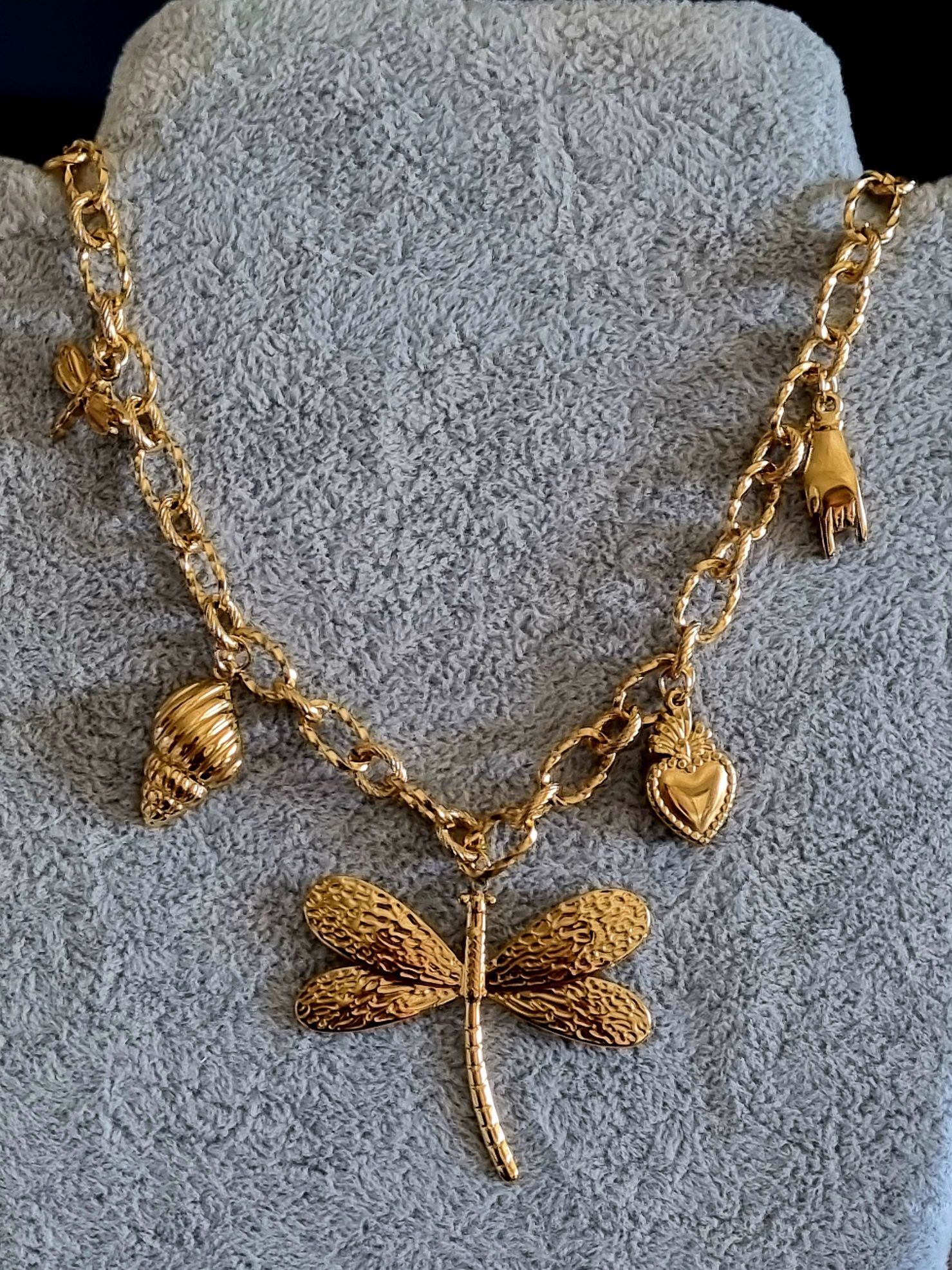 Colar dourado, em aço, com libelinha e mais 4 pingentes.