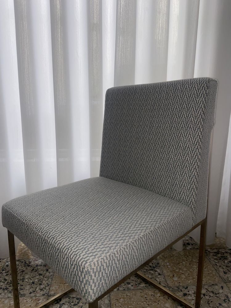 Cadeira em inox com acabamento dourado e cobertura em tecido