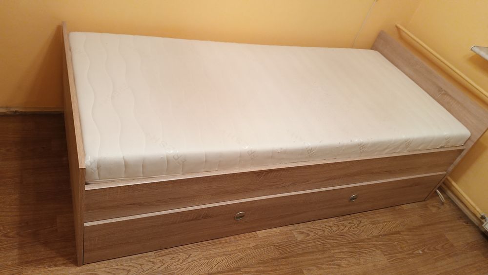 Łóżko jednoosobowe z szufladą na pościel, oraz materacem.