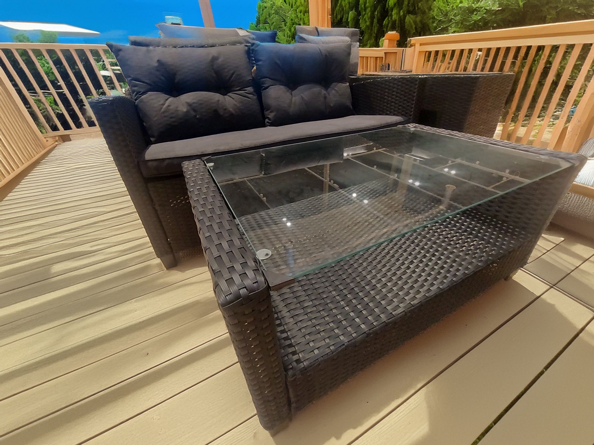 Meble ogrodowe sofa plus dwa fotele i stolik z drewnianym blatem.