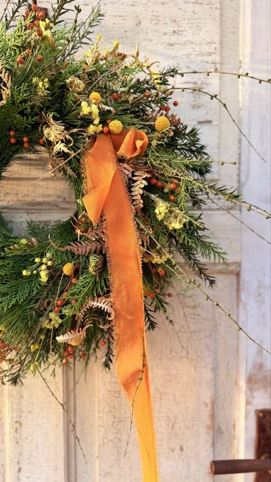 Jesienny wianek z gałązkami modrzewia i pomarańczową kokardą