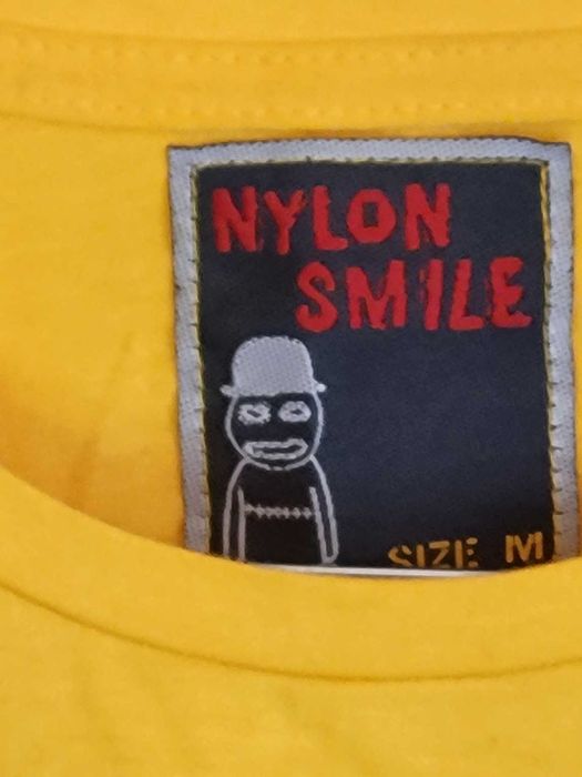 Żółta koszulka z kolekcji Nylon Smile, rozmiar M, nadrukiem bohaterów.