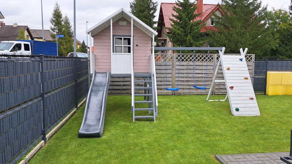 Duży drewniany domek dla dzieci ze zjeżdżalnią, huśtawkami, wspinaczką
