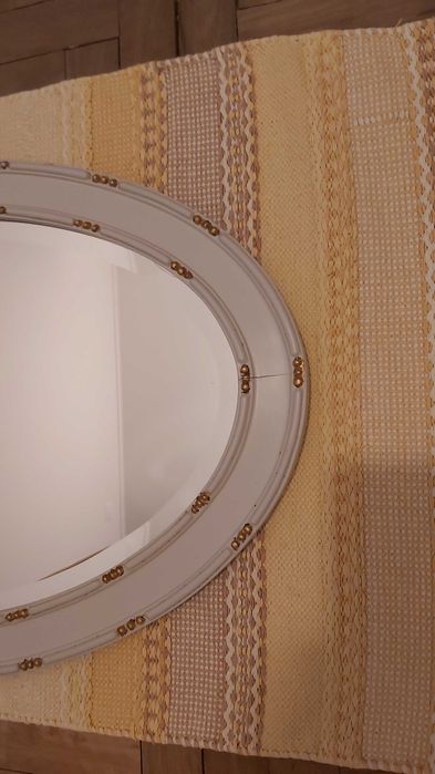 Espelho biselado com moldura de madeira com detalhes esculpidos.