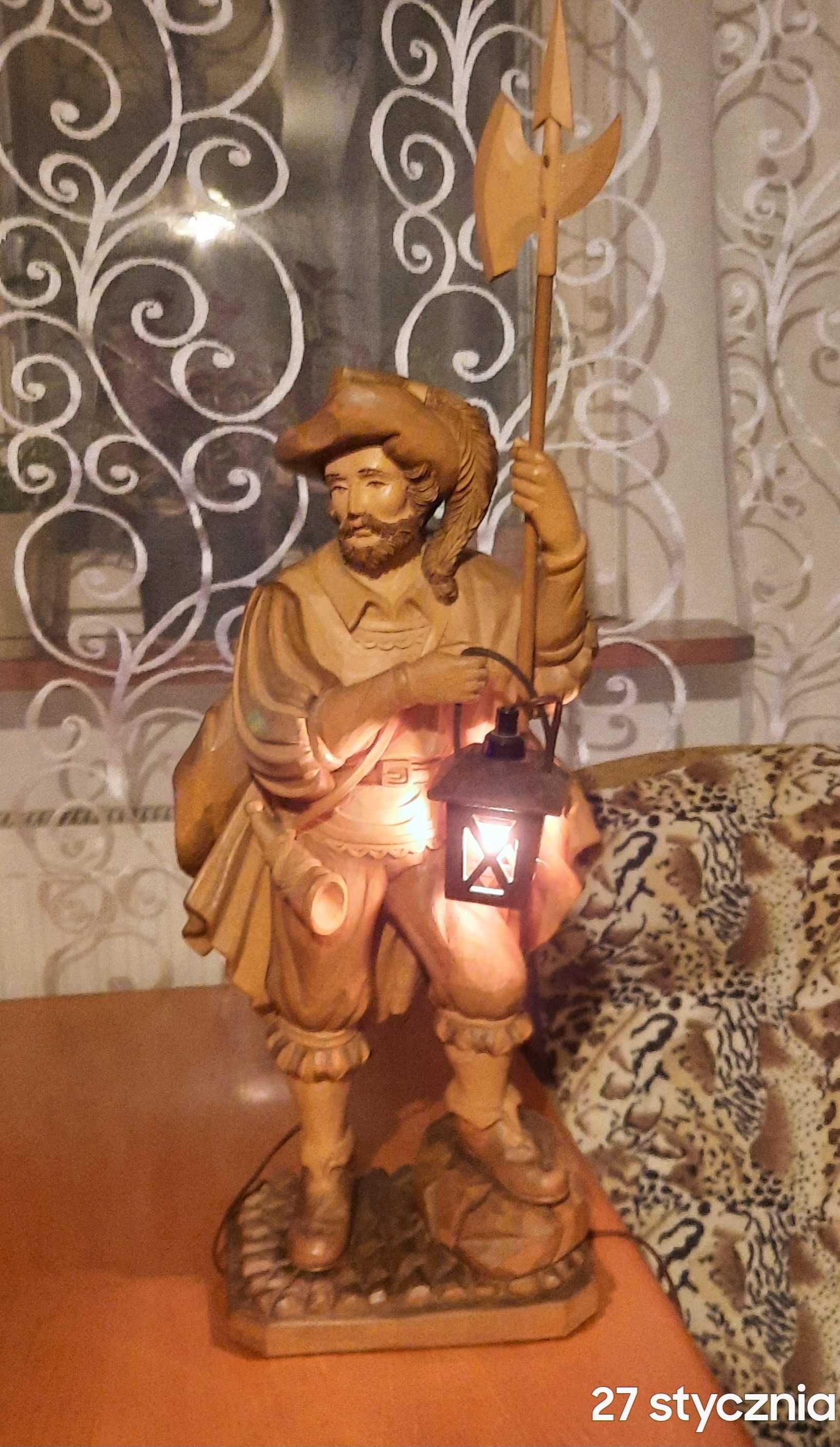 Drewniana rzeźba stroża z latarnią i halabardą.