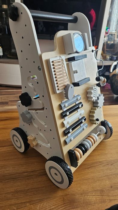 Interaktywny pchacz-jeździk dla dzieci, wykonany z drewna.