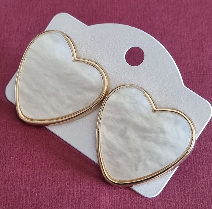 Brincos, de picos, com forma de coração branco delineado a dourado.