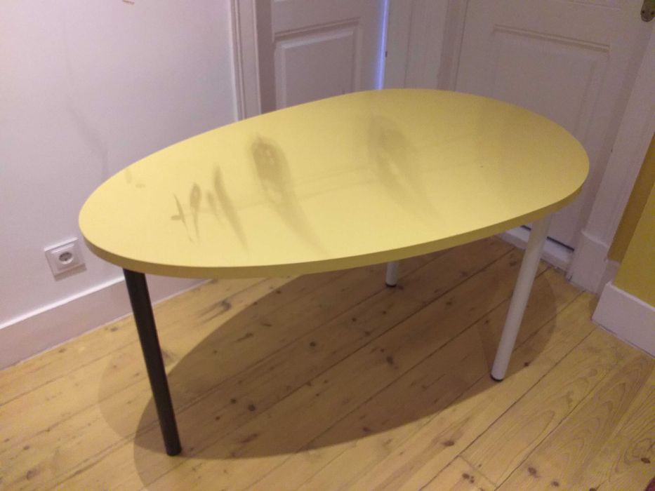 Mesa design oval com cor amarela, uso versátil.