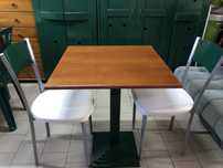 Mesa quadrada em ferro fundido com duas cadeiras almofadadas.
