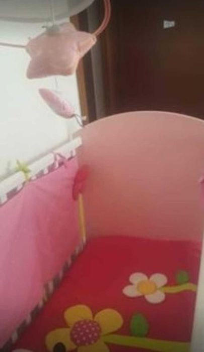 Cama de bebé rosa com colchão