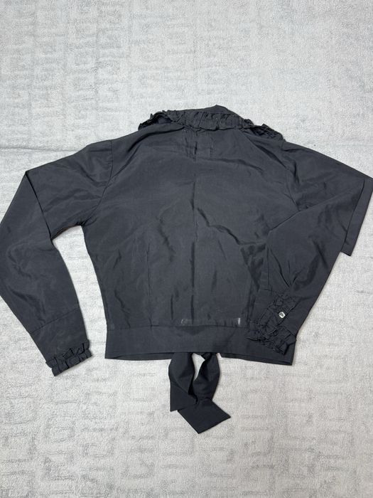 Чорна блузка з рюшами та зав'язками на талії.